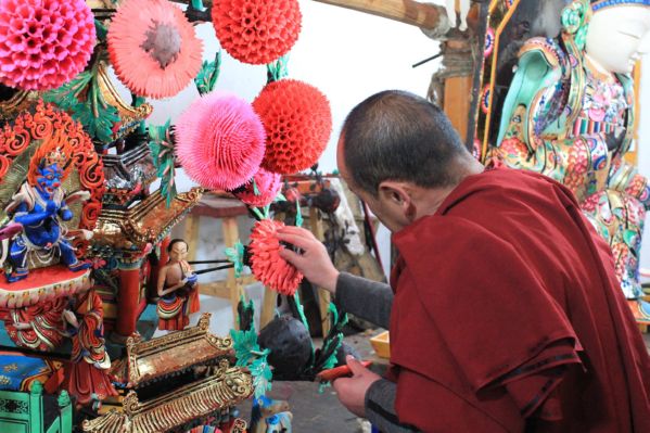 A Tibetan monk carves the intricate flowers on display