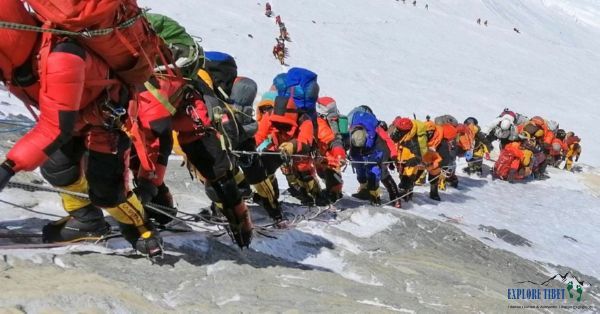 Hundreds of people queue on the sheer cliff face of the Southern Face of Mount Everest, waiting for their turn to reach the summit.