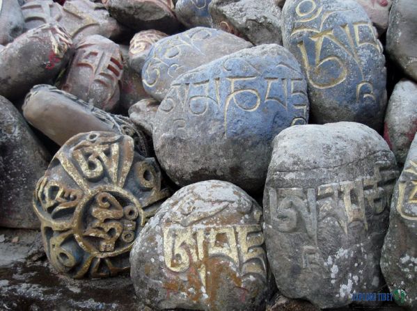Tibetan Mani Stones in a pile carved with the phrase 'Om Mani Padme Hum'.