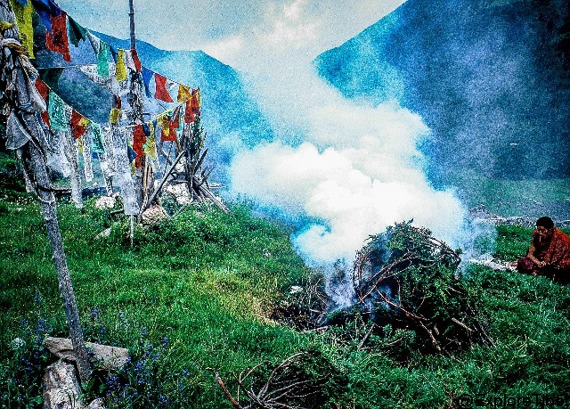 A Lama burns juniper branches to purify the air as he chants prayers to a local deity.