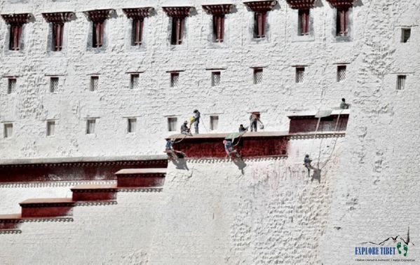Workers hang from the roofs to paint the high walls of the palace